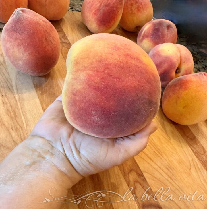 IMG_1929 | La Bella Vita Cucina Close-up of fuzzy peaches piled on a wooden surface.