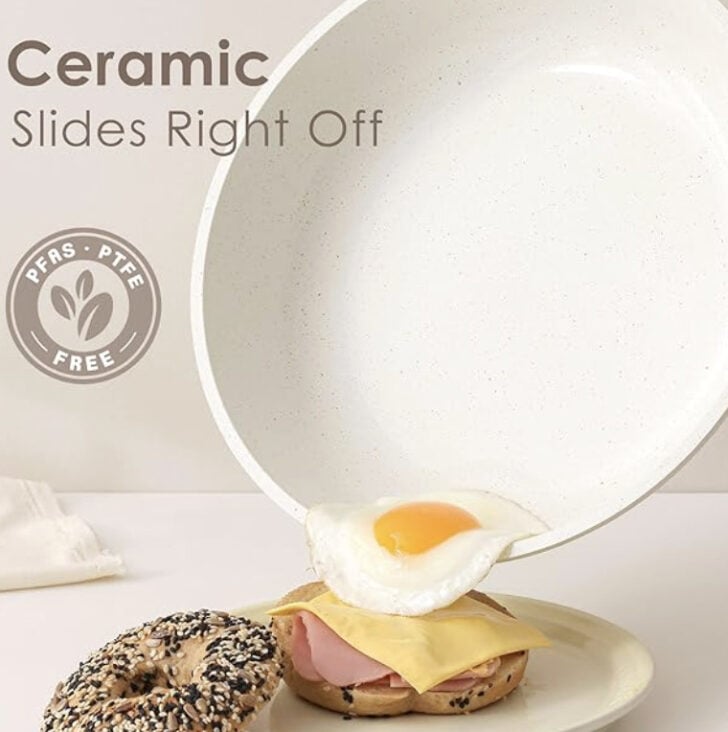 Fried egg sliding off a white ceramic plate onto a bagel with ham and cheese; branding reads'Ceramic Slides Right Off' with a PFAS/PTFE Free badge.